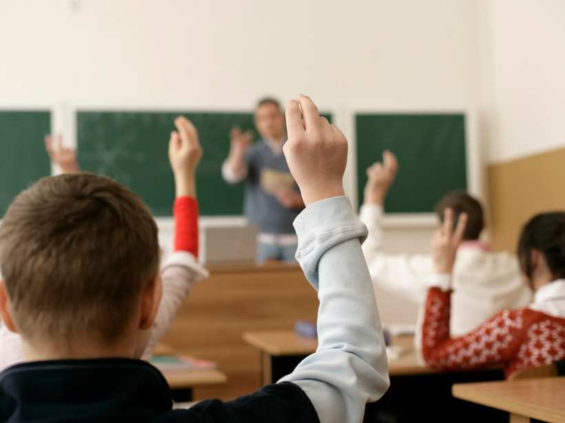 Leerlingen steken hun hand op in de klas